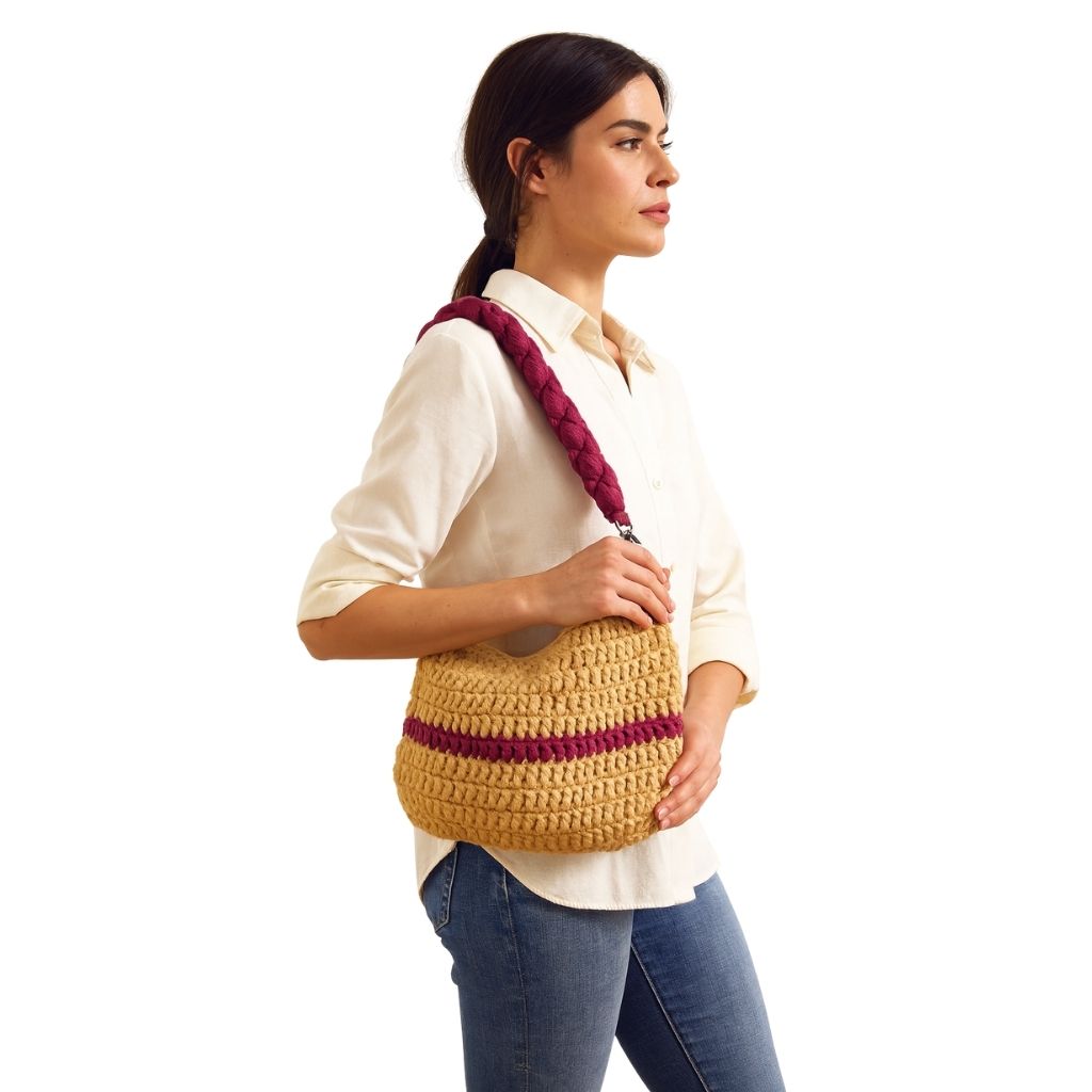 Woman holding a Beige handbag with a wine red straps