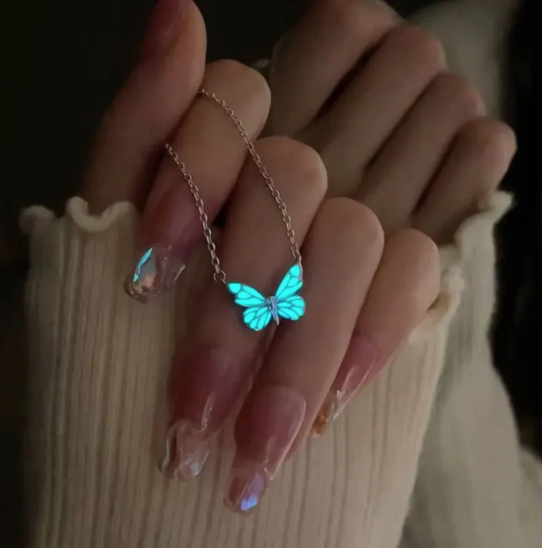 a glow-in-the-dark butterfly pendant necklace made of titanium steel with a white and blue color scheme, shown on a hand.