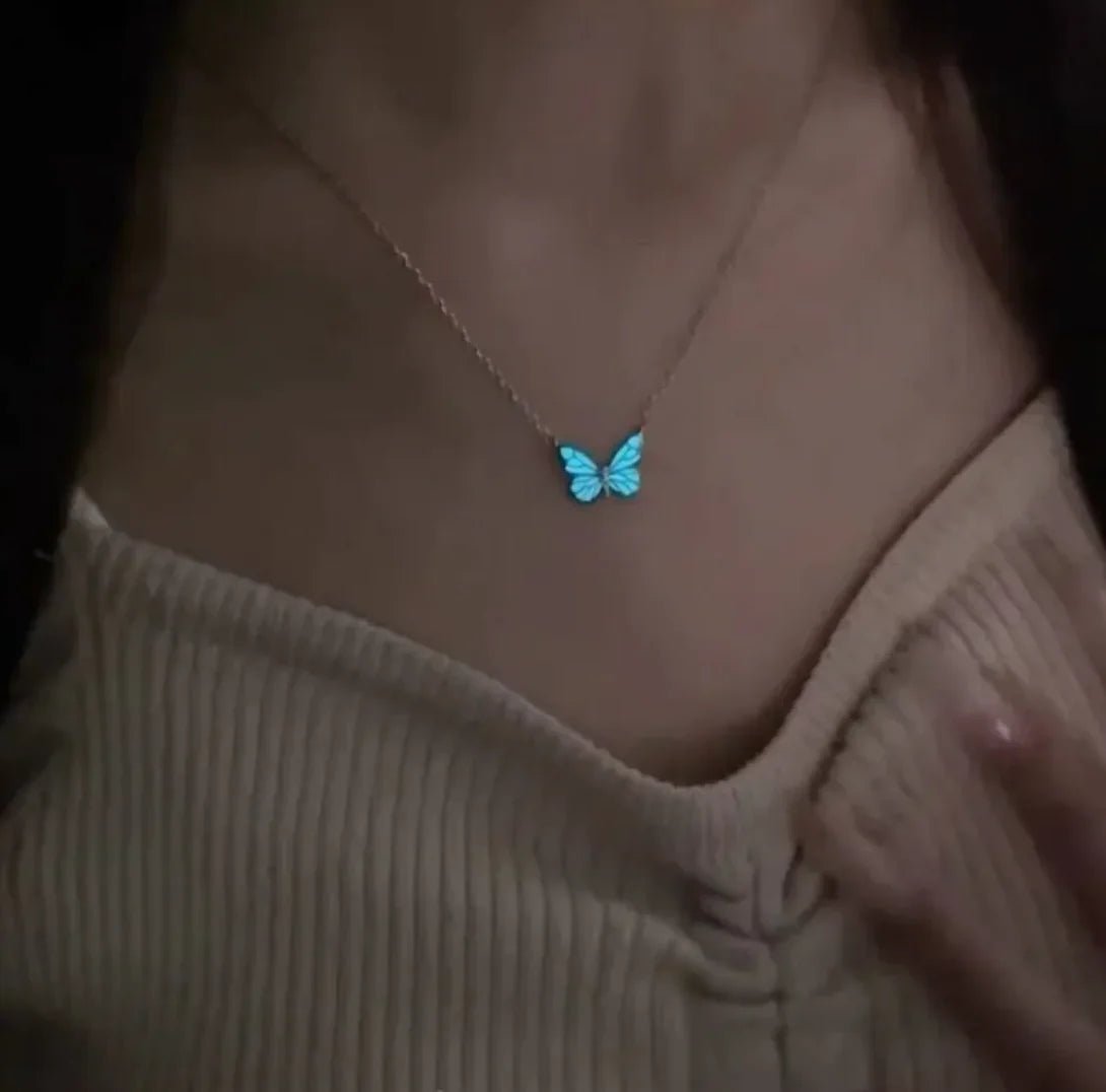 A person wearing a glow-in-the-dark butterfly pendant necklace made of titanium steel with a white and blue color scheme.
