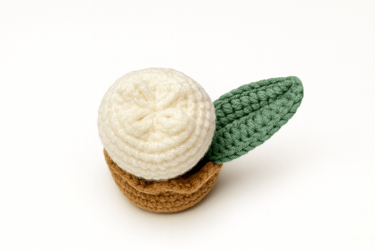 Crocheted potted plant with a white flower and green leaves