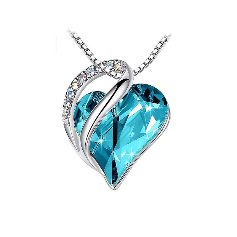 A heart-shaped pendant necklace with a Turquoise crystal pendant surrounded by smaller clear crystal.