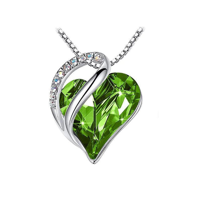 A heart-shaped pendant necklace with a Green crystal pendant surrounded by smaller clear crystal.