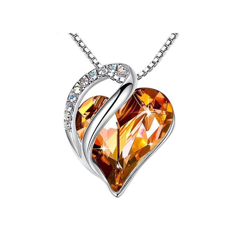 A heart-shaped pendant necklace with an Orange crystal pendant surrounded by smaller clear crystal.
