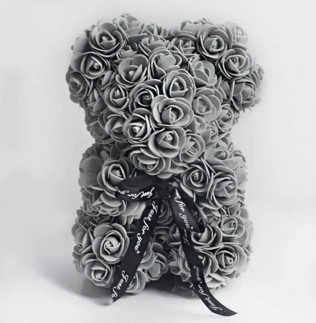 A teddy bear made from Grey artifical roses, with a black ribbon bow.