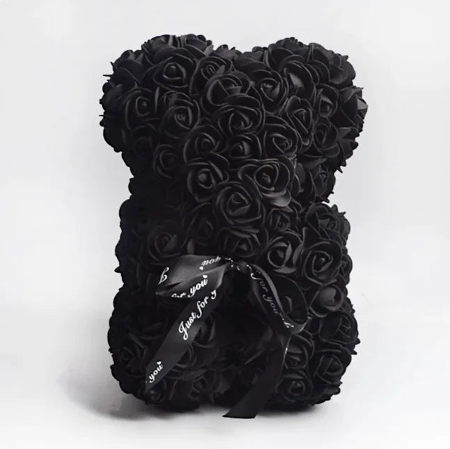 A teddy bear made from Black artifical roses, with a black ribbon bow.