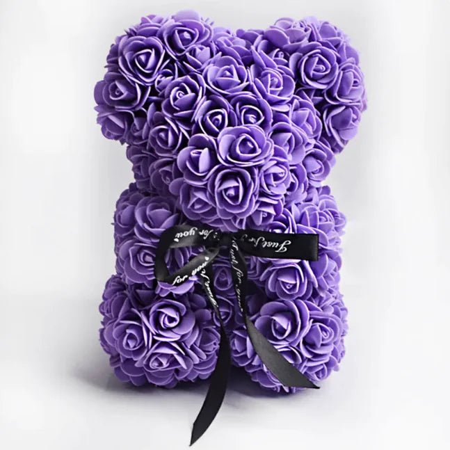 A teddy bear made from purple artificial roses, with a black ribbon bow.