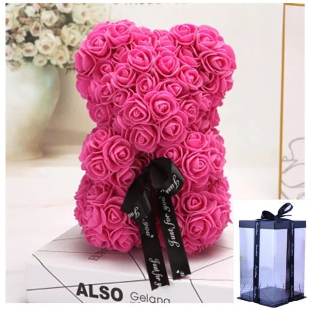 A teddy bear made from Dark pink artifical roses, with a black ribbon bow, comes with a box.