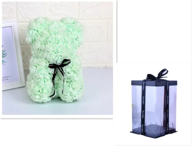 A teddy bear made from Light Green artifical roses, with a black ribbon bow, comes with a box.