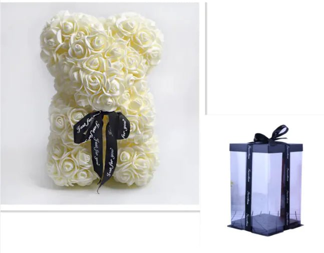 A teddy bear made from Beige artifical roses, with a black ribbon bow, comes with a box.