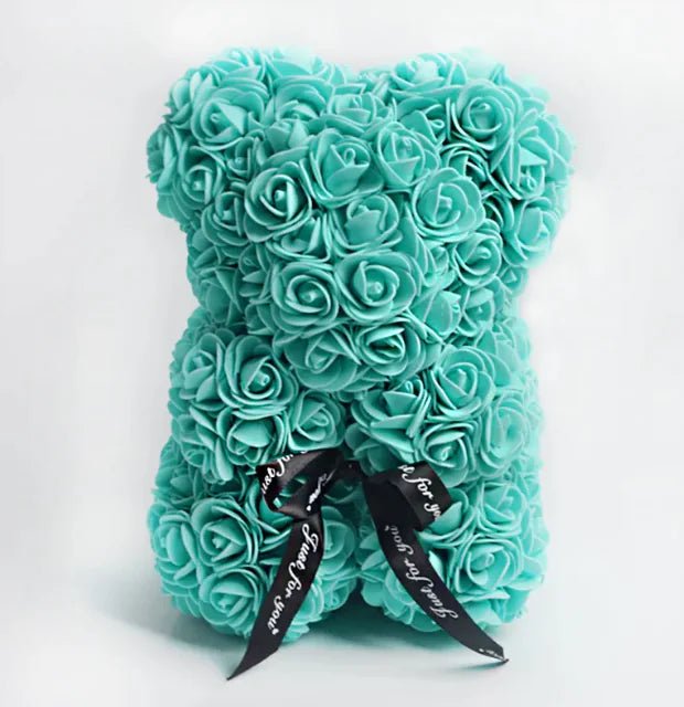 A teddy bear made from Turquoise artificial roses, with a black ribbon bow, comes with a box.