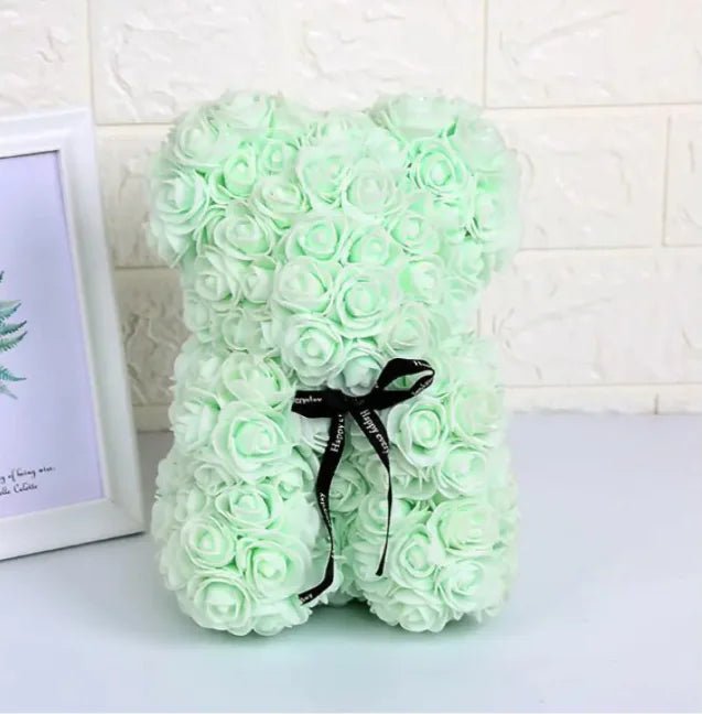 A teddy bear made from Light Green artifical roses, with a black ribbon bow.