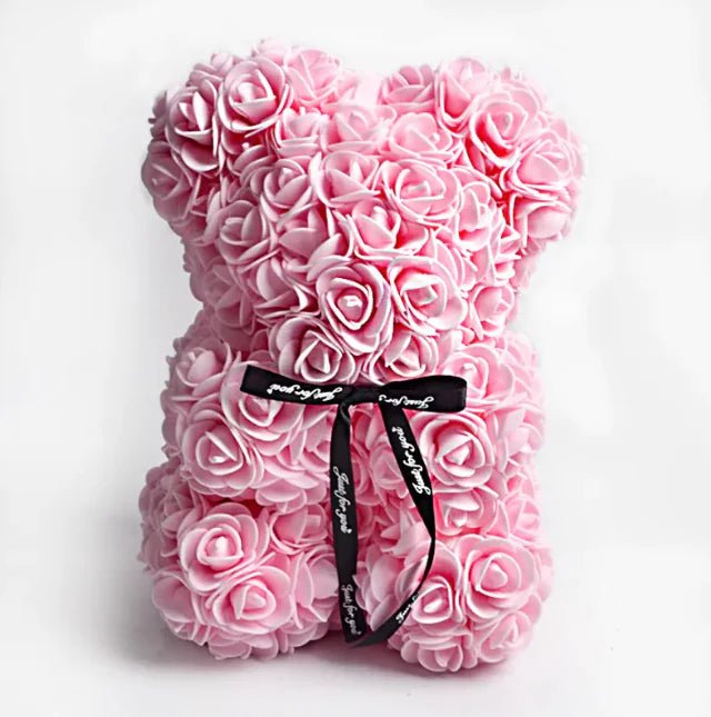 A teddy bear made from Light pink artificial roses, with a black ribbon bow.