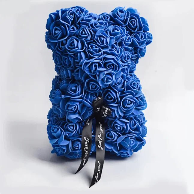 A teddy bear made from Royal Blue artificial roses, with a black ribbon bow.