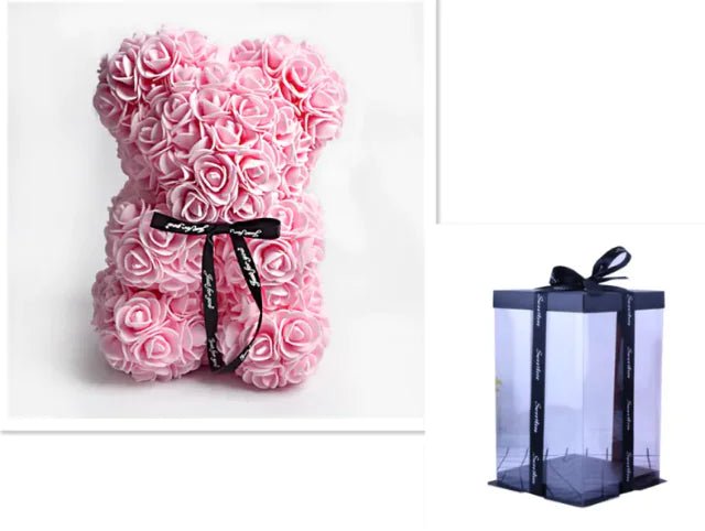 A teddy bear made from Light pink artificial roses, with a black ribbon bow, comes with a box.