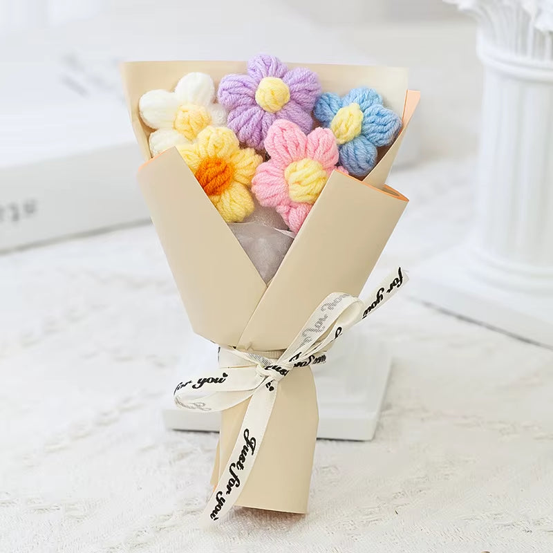 Bouquet of colorful knitted flowers wrapped in beige paper with a white ribbon.
