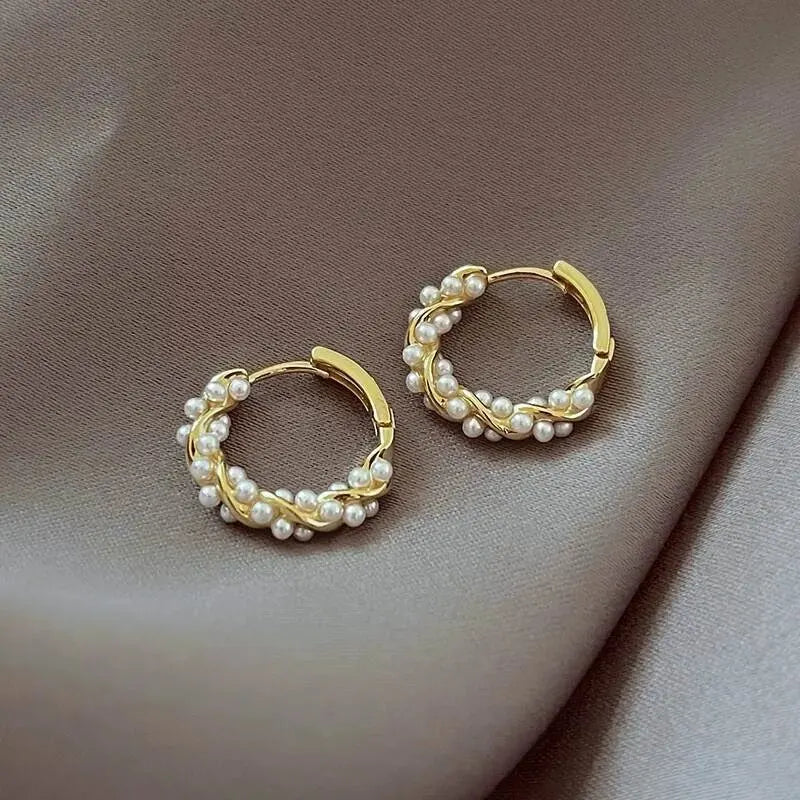 Gold hoop earrings with pearl beads on a brown surface
