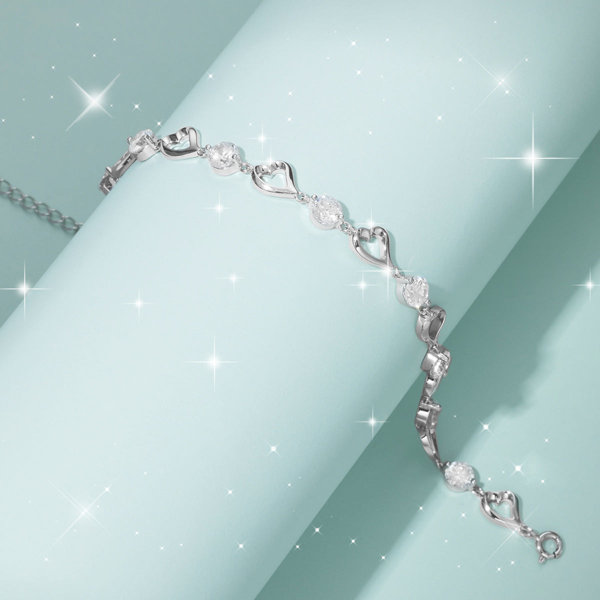 Silver bracelet with heart and diamond designs on a light blue background