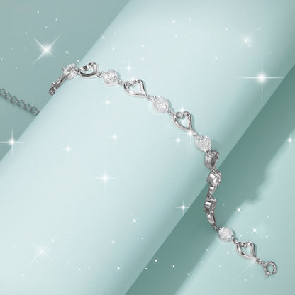 Silver bracelet with heart and diamond designs on a light blue background