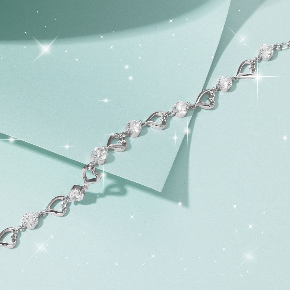 Silver bracelet with heart and leaf designs on a light blue background