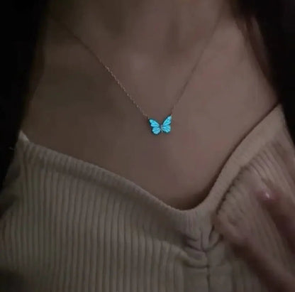 A person wearing a glow-in-the-dark butterfly pendant necklace  made of titanium steel with a white and blue color scheme.