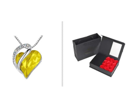 A set of a heart-shaped pendant necklace with a Yellow crystal pendant surrounded by smaller clear crystal and a box.