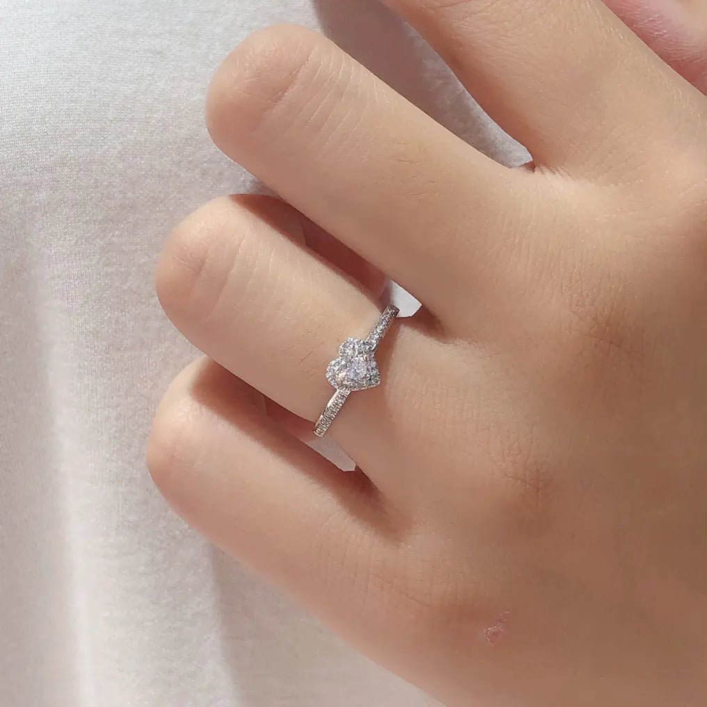 A sterling silver heart-shaped ring with a platinum-colored finish, shown on a hand.