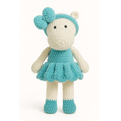 Handmade crochet doll in the shape of a hippopotamus wearing a teal dress and matching bow headband.