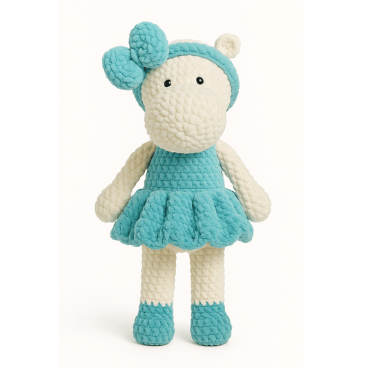 Handmade crochet doll in the shape of a hippopotamus wearing a teal dress and matching bow headband.