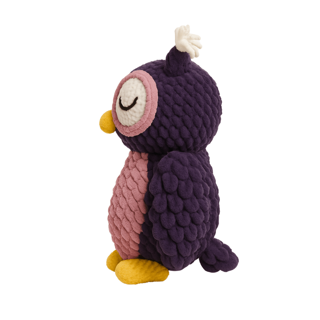 Handmade crochet plush owl with deep purple feathers, pink chest, and gold feet, with a peaceful closed-eye expression