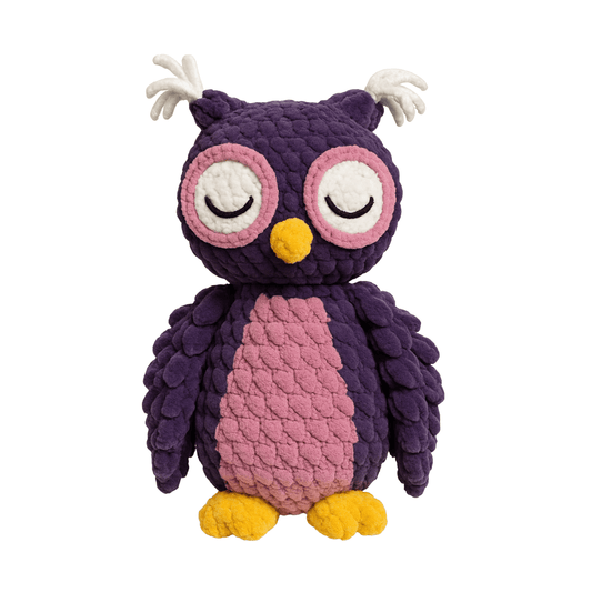 Handmade crochet plush owl with deep purple feathers, pink chest, and gold feet, with a peaceful closed-eye expression.