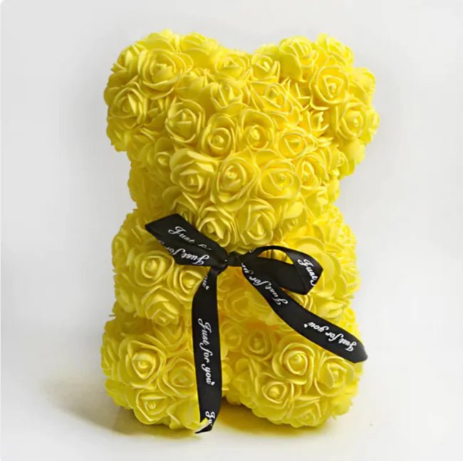 A teddy bear made from Yellow artifical roses, with a black ribbon bow.