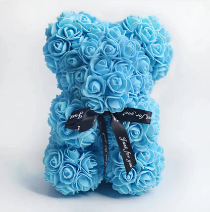 A teddy bear made from Sky blue artificial roses, with a black ribbon bow.