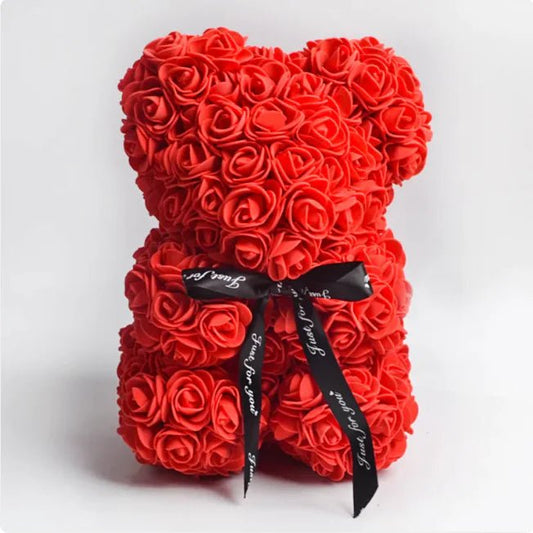 A teddy bear made from red artificial roses, with a black ribbon bow