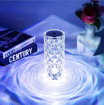 A crystal table lamp on a reflective surface with a blue light